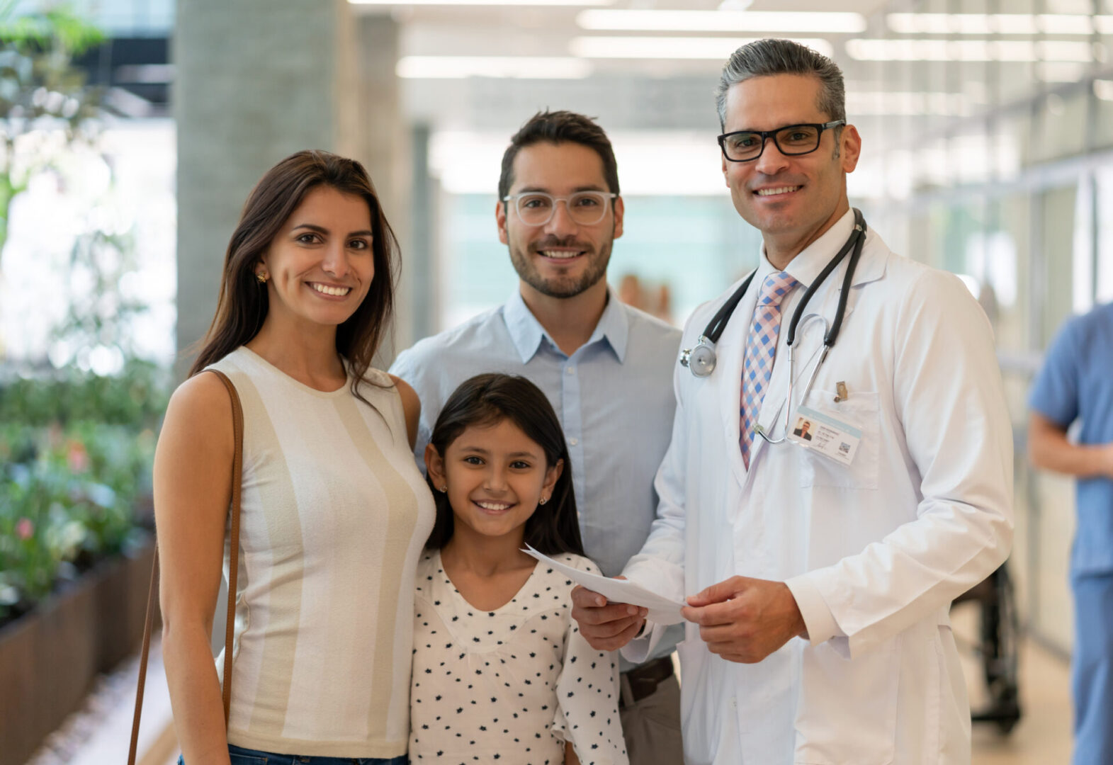 Doctor with smiling family in hospital hallway.