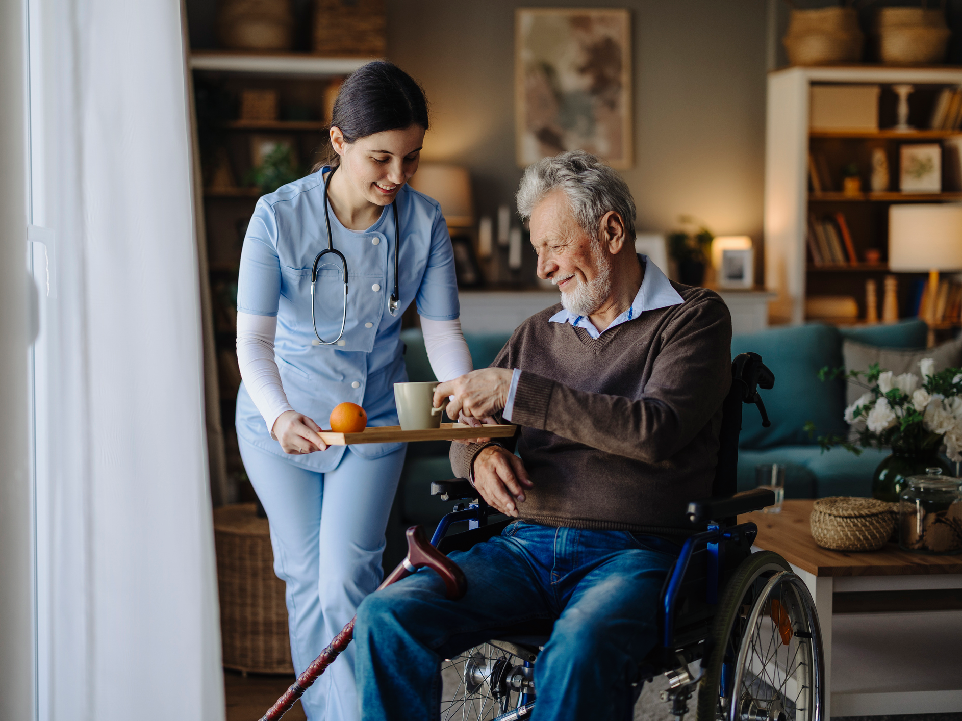 Nurse assisting elderly man in wheelchair.