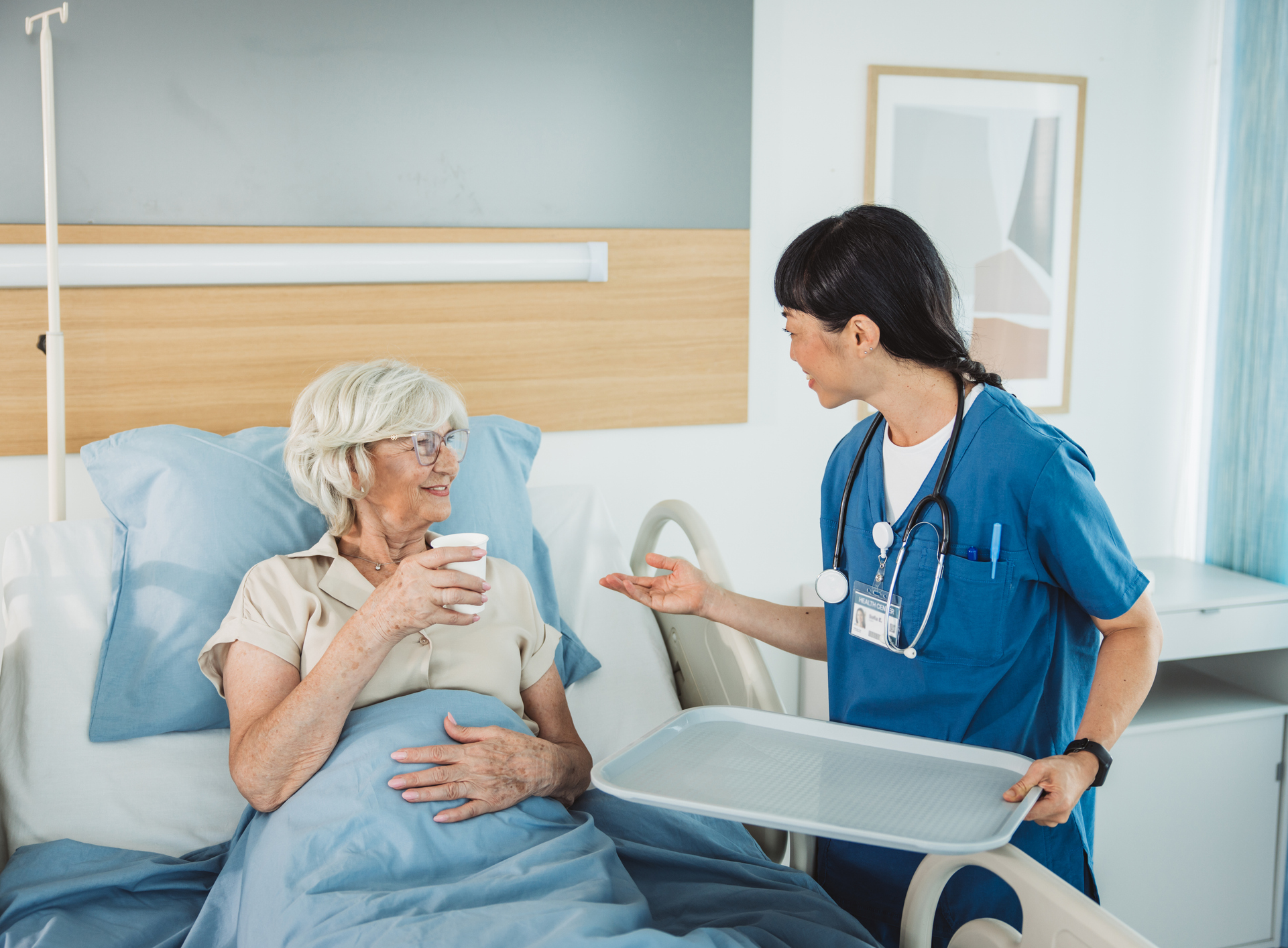 Nurse talking to patient in hospital bed.