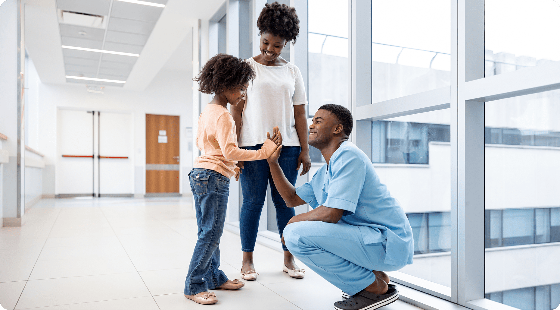 Nurse high-fiving child in hospital hallway.